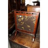 An Aesthetic movement mahogany framed fire screen inset bird and foliate decorated oriental silk
