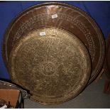 A large silvered copper tray with engraved decoration, a brass mounted circular table top with