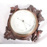 A barometer with white enamel dial and fruit carved oak case