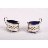 A pair of Victorian silver teardrop-shaped salts with pierced decoration and blue glass liners,