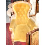 A Victorian mahogany framed spoon back armchair, upholstered in a gold velour, on turned supports