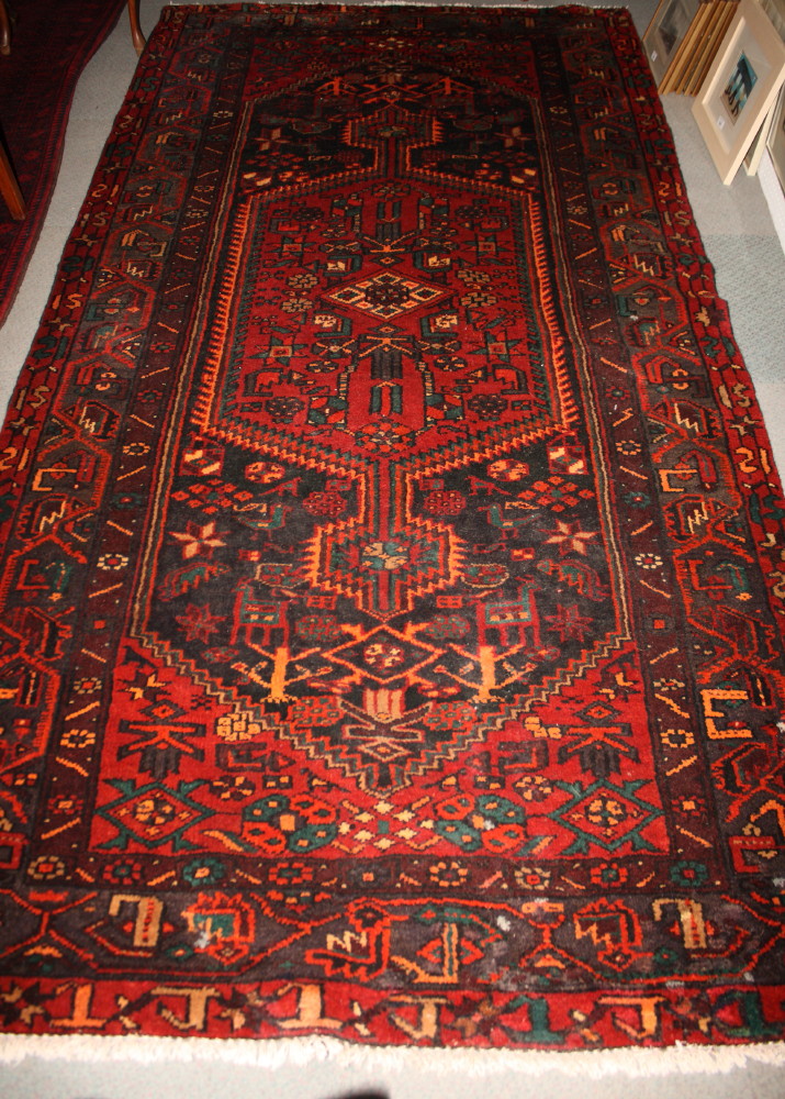 A Hamadan wool rug decorated central red anchor medallion and stylised flowers on a dark blue