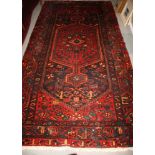 A Hamadan wool rug decorated central red anchor medallion and stylised flowers on a dark blue
