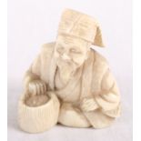 An ivory netsuke of a seated figure with a basket, signed