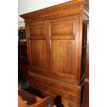 A George III oak cupboard with hanging rail enclosed two twin panelled doors, fitted seven drawers