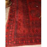 An Afghan carpet decorated twenty-one guls on a red ground and multi-bordered, 160" x 111" approx