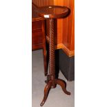 A mahogany torchere on spiral reeded stem and tripod base and an oval wall mirror in mahogany frame