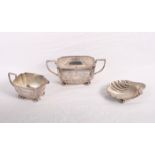 A silver shell-shaped butter dish, a lidded silver sugar bowl and a matching milk jug