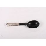 A white metal beaker and a white metal handled ebony serving spoon