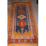 A North African gold wash tribal rug decorated three hooked medallions on a blue ground, 37" x 72"