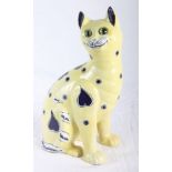 A Galle style ceramic model of a seated cat decorated in blue on a pale yellow ground, glass eyes,