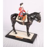A Coalport china figure, "Trooping the Colour", on ebonised base (riding crop restored)
