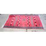 A Caucasian rug decorated bands of stylised ornaments on a pink ground with four border stripes, 70"