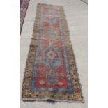 A Persian tribal runner of traditional design with fourteen diamond lozenges in shades of blue, plum