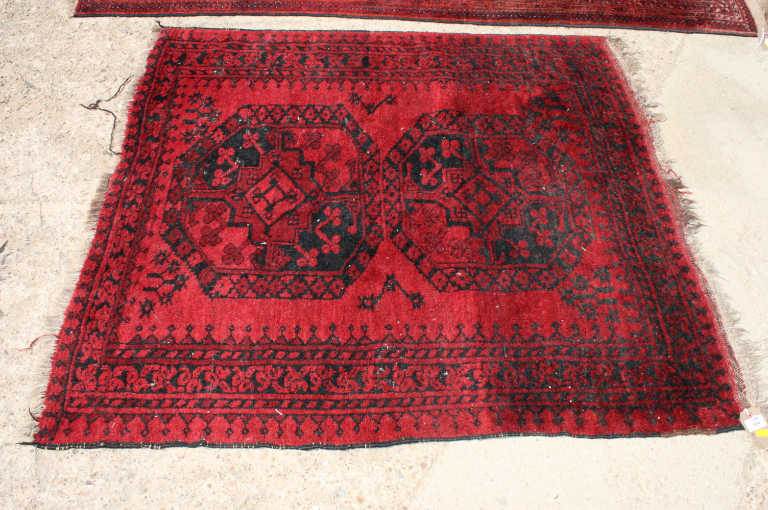 A Bokhara rug decorated two medallions on a red ground, 47" x 43" approx (worn)