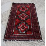 A Caucasian rug decorated three medallions on a red ground, 63" x 33" approx