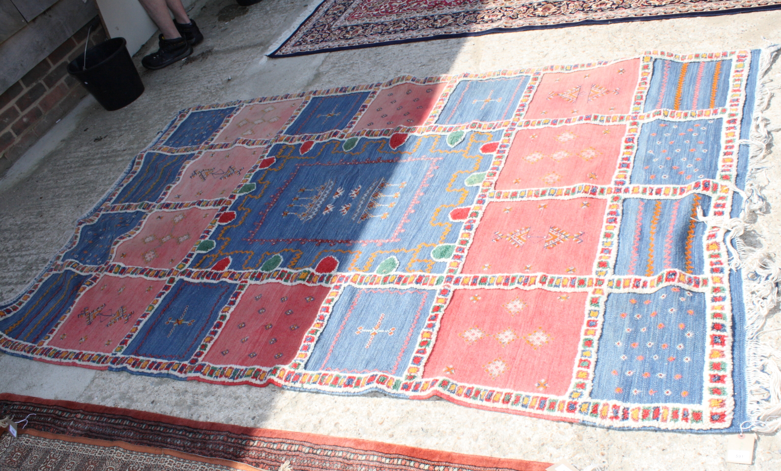 A Caucasian tribal rug decorated candlesticks on central blue ground panel surrounded by pink and