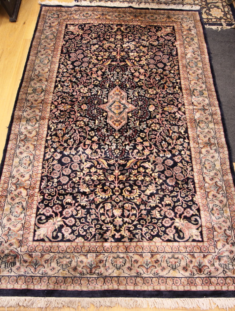 A Persian design rug with all-over floral and scroll design on a dark blue ground, 77" x 48" approx