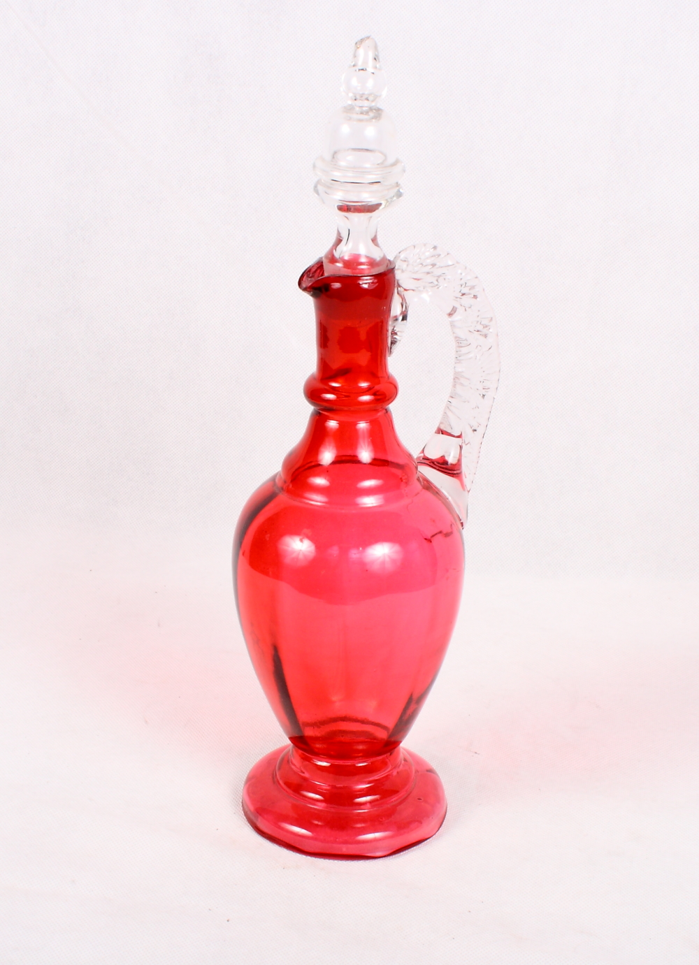 A cranberry glass jug and stopper with pinched handle, 13 1/2" high overall