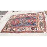 A Caucasian tribal rug decorated three hooked guls on a tribal ground, 72" x 46" approx (worn)