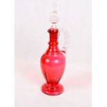 A cranberry glass jug and stopper with pinched handle, 13 1/2" high overall
