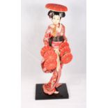 A mid 20th Century Japanese figure of a geisha in full costume, on ebonised base, 21" high