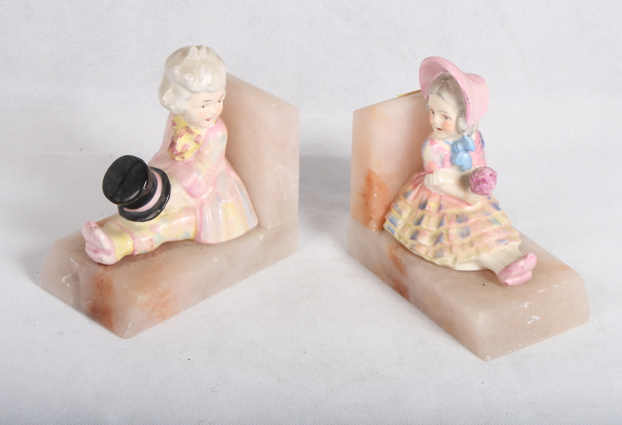 A pair of early 20th Century porcelain and onyx bookends with children in period costume, 4 1/2"