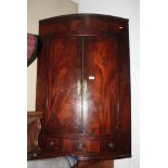 A Georgian mahogany bowfront wall hung corner cabinet decorated ebony stringing, fitted drawer