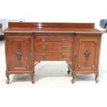 An early 20th Century mahogany inverse breakfront sideboard, fitted cupboards and two short and