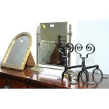 A pair of wrought iron fire dogs, a brass framed dressing mirror with Corinthian column standards