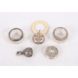 A silver circular pill box with repousse decorated top, a silver bell, a silver plated bell with