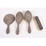 A pair of repousse silver backed hair brushes, a similar white metal mirror frame and a silver