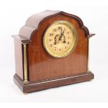 An early 20th Century mahogany and banded arch top mantel clock with gilt dial and brass flanking