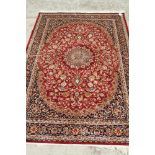 A Kashan design carpet decorated central medallion with blue spandrels and border on a red ground,