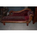 A Victorian mahogany framed scroll end settee, upholstered in a red velvet, on turned supports,