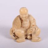 A 19th Century Japanese carved ivory okimono of a seated man holding a fan and scroll, another of