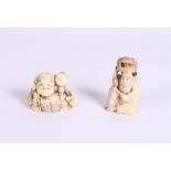 A Japanese carved ivory netsuke formed as a seated male with a rat and a small carved ivory
