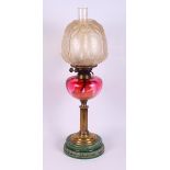 A brass, ruby glass and ceramic table oil lamp with chimney and frosted shade, 25" high