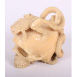 A 19th Century Japanese carved ivory okimono formed as a human skull mounted three toads, one