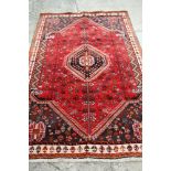 A Persian handmade rug decorated central medallion on a red floral ground with blue corners and