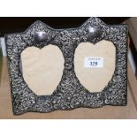 A silver mounted double photograph frame with embossed foliate decoration and heart-shaped