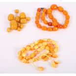 A string of graduated egg yolk coloured amber beads, 51g, a string of amber coloured beads and a