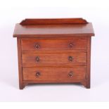An Edwardian mahogany miniature chest of three long graduated drawers, on bracket supports, 10"