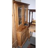 A late 19th Century waxed pine shape front dresser, the upper section enclosed two glazed panel