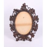 A 19th Century Black Forest carved wood oval easel frame, 13" high (old damages)
