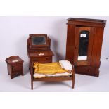 A doll's 1920s mahogany bedroom suite including wardrobe, dressing chest, bedside chest and bed,