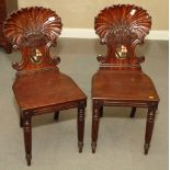 A pair of mid 18th Century carved mahogany shell back hall chairs with painted coat of arms and
