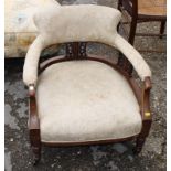 A late 19th Century walnut showframe low tub seat chair, on castored supports