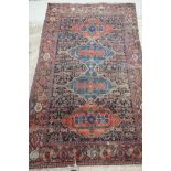 A Persian tribal rug decorated four large lozenges on a rust ground and multi-bordered in shades