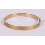 A 9ct gold bangle with engine turned decoration, 30.2g